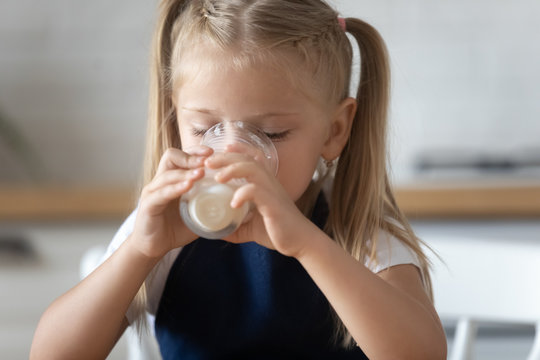 Closeup image little girl holds a glass drinks milk