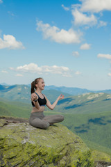 Naklejka na ściany i meble Girl doing yoga exercise lotus pose at the top of the mountain.