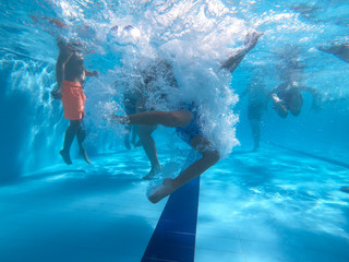Underwater view from kids dive into a pool in a summer day
