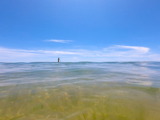 Ocean clear water and blue sky with a young man practice paddle boarding . Algarve Portugal