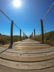 Wooden footpath through dunes in the Atlantic ocean coast. Guincho beach at sunset, Cascais Portugal