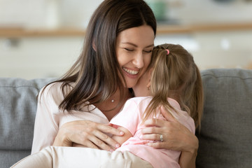 Mother holding on lap daughter embraces her enjoy tender moment
