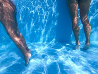 Underwater view from two girls in bikini standing in a pool