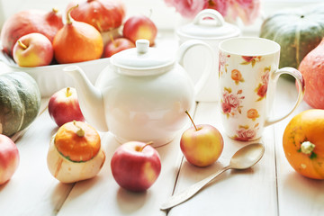 Thanksgiving Day table. Happy Halloween. Pumpkins, apples and flowers. Tea set on window background.  Bright autumn background. Colorful autumn card. Autumn flower arrangement. Autumn bouquet.