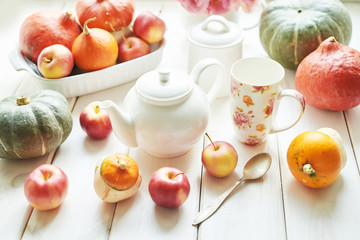Thanksgiving Day table. Happy Halloween. Pumpkins, apples and flowers. Tea set on window background.  Bright autumn background. Colorful autumn card. Autumn flower arrangement. Autumn bouquet.