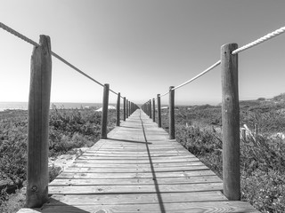 Wooden footpath through dunes in the Atlantic ocean coast. Guincho beach at sunset, Cascais Portugal