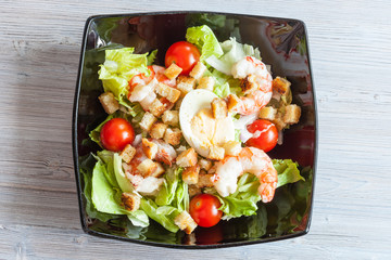 top view of Caesar salad with prawn on black plate