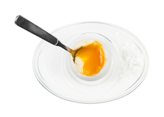 top view of open egg with spoon in glass egg cup