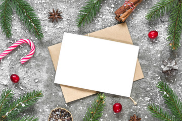 Christmas greeting card in frame made of fir branches, decorations, berries, candy and pine cones