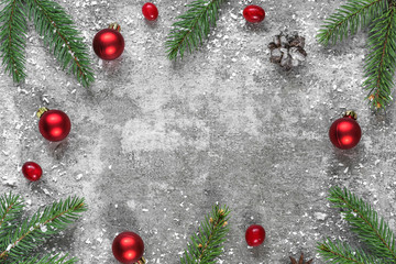Christmas frame made of fir branches, decorations, berries and pine cones on concrete background