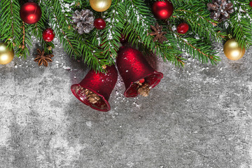 Christmas background with fir branches, red and golden decorations, berries and pine cones on concrete background