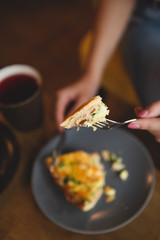 the process of eating girls in a cafe. Close up Photo of female hands holding fork and knife cutting a piece of salty pie