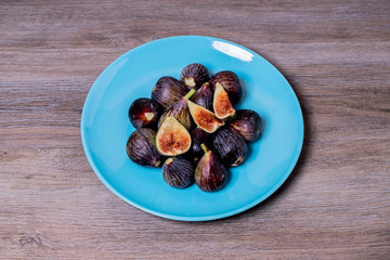 Higos ecológicos sobre plato azul y fondo de madera
