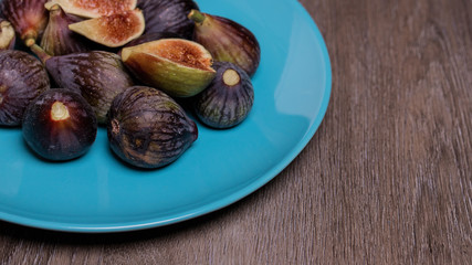 Higos ecológicos sobre plato azul y fondo de madera