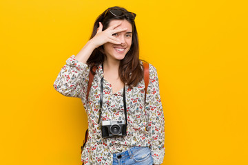 Young brunette traveler woman blink at the camera through fingers, embarrassed covering face.