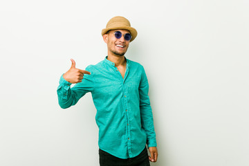 Young hispanic man wearing a summer clothes person pointing by hand to a shirt copy space, proud and confident