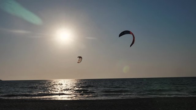 Kyte surfers on the sea waves at dusk