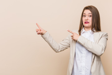 Fototapeta premium Young business woman shocked pointing with index fingers to a copy space.