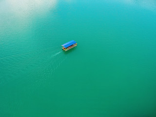 Aerial view of Jablanicko lake in Bosnia and Herzegovina near village Ostrozace with small boat with blue roof sailing on turquoise water