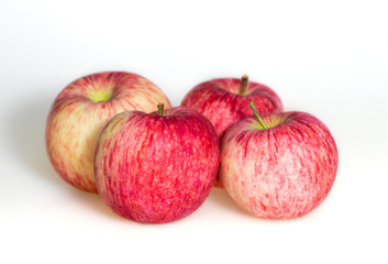 Four apples on white background. Red juicy ripe apples close up. Fresh striped fruit. Side view.