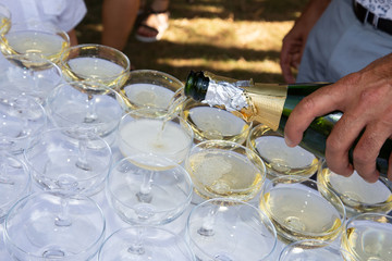 waiter does champagne service outdoors in toasting glasses