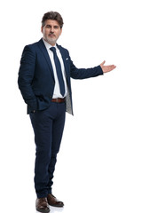 Serious looking businessman presenting and holding his hand in his pocket