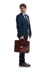 Nervous businessman looking over his shoulder and holding a suitcase