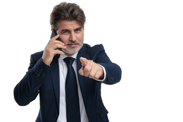 Elegant businessman pointing and talking on his phone