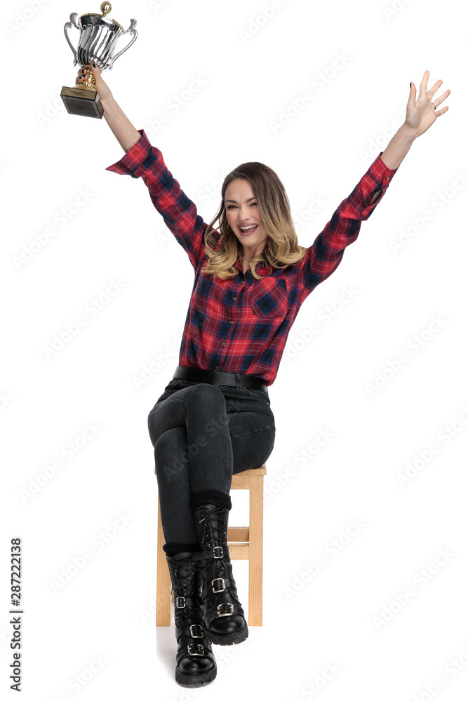 Poster casual woman sitting with hands in air and trophy