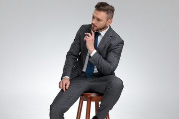 pensive young businessman sitting on stool and wonders