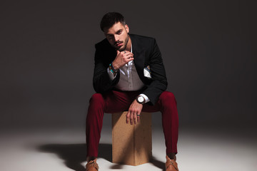 pensive young attractive man sitting on wood box