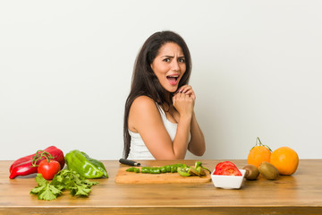 Young curvy woman preparing a healthy meal scared and afraid.