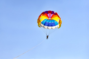 Para sailing using a parachute on background of blue sky.