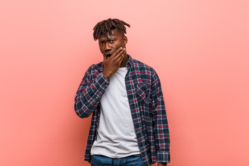 Young african black man thoughtful looking to a copy space covering mouth with hand.