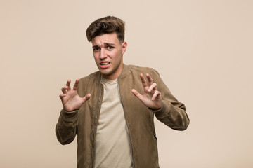 Young caucasian man wearing a brown jacket rejecting someone showing a gesture of disgust.