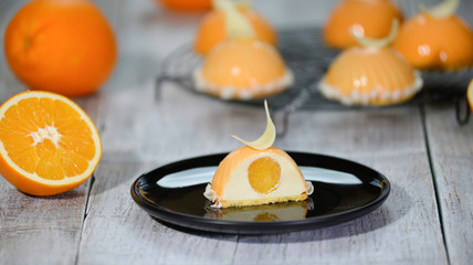 French mousse cake covered with orange glaze decorated with white chocolate. Modern european cake pastry.