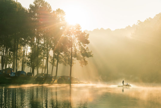 Photographer standing to take pictures on a wooden raft float , Beautiful nature and pine forest in the morning at Pang Ung(Pang Tong Reservoir) in Mae Hong Son Province, North of thailand