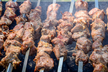 Grilled kebab cooking on metal skewer. Roasted meat cooked at barbecue. BBQ fresh pork meat chop slices. Eastern dish, shish kebab. Grill on charcoal and flame, picnic, street food.