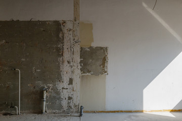 Interior view of old crack damaged white wall. Abandon empty room. Indoor space of renovating construction site. 