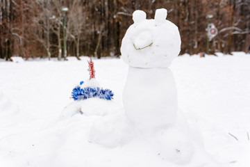 Snowman in the form of cat standing on the background of white snowdrifts in the winter landscape. A lot of snow.