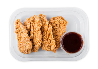 Southern breaded chicken in plastic tray with barbecue sauce on white background.