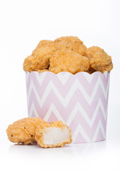 Crunchy chicken popcorn bites in kids paper cup for fast food meals on white background.