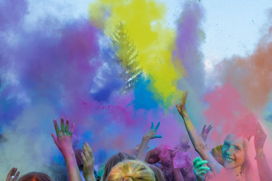 Begeisterte Kinder auf einem Holi Fest tanzen und werfen mit buntem Farbpulver	