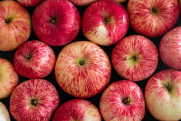 Red apples fruit background. Flat lay. Beautiful ripe fresh striped apples on a black table close up. Food background. Top view, macro. Autumn harvest.