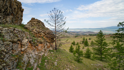 Fototapeta na wymiar Baikal region. Dirt road on Tazheranskaya steppe near the stone rocks, called the Valley of the Stone Spirits.