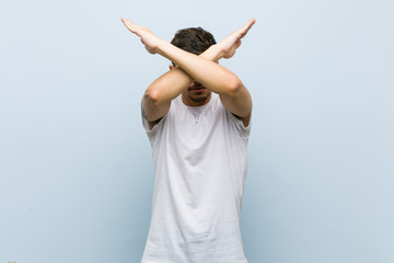 Young caucasian man wearing a white tshirt keeping two arms crossed, denial concept.