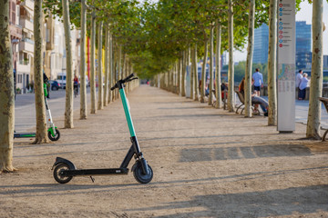 One E-scooters, Eco friendly and trendy mobility urban lifestyle, park on promenade riverside of Rhine River in Düsseldorf, Germany with background of diminishing perspective line of trees . © Peeradontax
