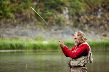 Fisherman casting catches fish in the river.