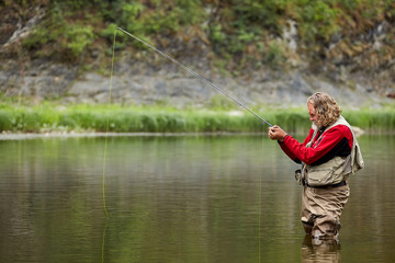 Casting angler catches fish in the river.