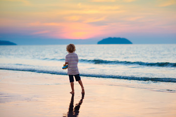 Fototapeta na wymiar Child playing on ocean beach. Kid at sunset sea.